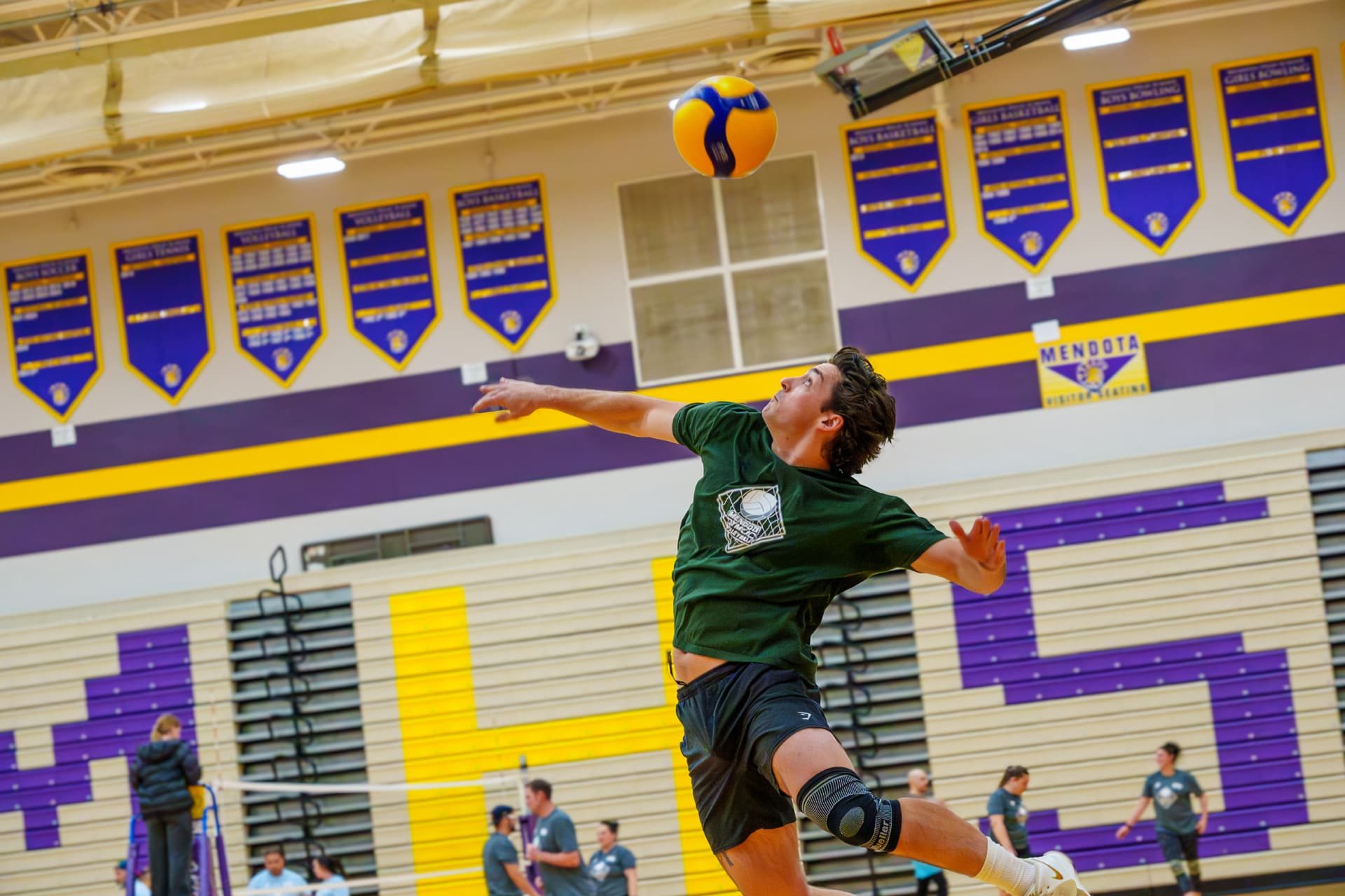 An adult league volleyball player leaping to spike the ball in the Mendota gym